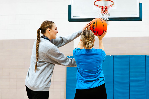 Girl learning to play basketball from her coach