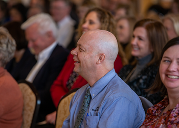 Smiling man in a seated crowd